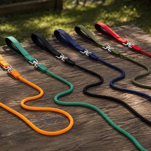May include: A collection of six dog leashes in orange, green, black, blue, olive, and red. Each leash features a thick, rounded rope design, a padded handle loop, and a silver-toned metal swivel snap hook for secure attachment to a collar or harness.