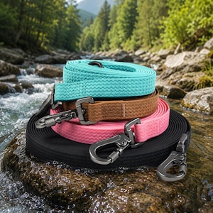 May include: A stack of four dog leads in turquoise, tan, pink, and black. Each lead features a textured, zigzag-patterned strap and a matte black metal swivel snap hook attached to one end for secure fastening to a collar or harness.