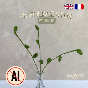 Peut inclure: Une tige de feuillage au crochet vert faite à la main dans un vase en verre transparent. Les tiges ont de petites feuilles rondes et sont étiquetées "MY FOLIAGE STEM PATTERN PDF". L'image comprend également un logo "ATELIER Alderi".