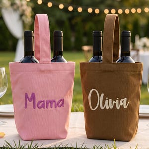 May include: Two fabric wine bottle bags with handles, one pink with the embroidered name Mama in purple, and one brown with the embroidered name Olivia in white. Each bag holds two dark glass wine bottles, positioned on a table with wine glasses.