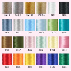May include: A grid of twenty-four cylindrical spools of embroidery thread in various colours, including metallic gold, silver, black, white, red, blue, green, yellow, and pink. Each spool is labelled with a unique alphanumeric code below it.