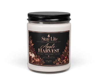 May include: A 9 oz candle in a clear glass jar with a black lid. The label features the text Stay Lit, Apple Harvest, Crisp Apple, Warm Cinnamon, Fall Spice, and Hand Poured With Love, decorated with illustrations of pumpkins and autumn leaves.