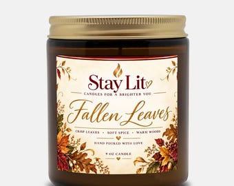 May include: A 9 oz candle in an amber glass jar with a gold metal lid. The label features the text Stay Lit, Fallen Leaves, Crisp Leaves, Soft Spice, Warm Woods, and Hand Poured With Love, decorated with illustrations of colorful autumn leaves.