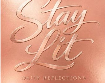 May include: A rose gold journal cover with a metallic finish featuring the embossed text Stay Lit in a large cursive script font and the smaller text DAILY REFLECTIONS in a clean sans-serif font centered below the main title.