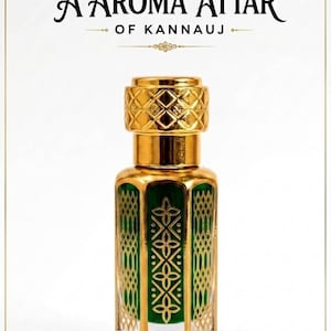 Op de afbeelding: Een glazen parfumflesje met een groene behuizing en goudkleurige metalen accenten, voorzien van een dop met ruitpatroon en gedetailleerde gouden filigraanontwerpen. De tekst A AROMA ATTAR OF KANNAUJ staat in decoratief lettertype boven de fles.