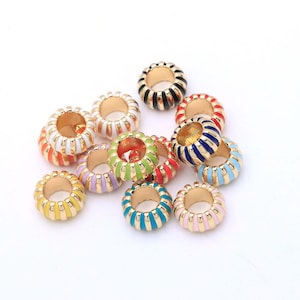 Peut inclure: Une collection de petites perles rondes en métal doré avec des stries verticales et des revêtements en émail coloré. Les perles sont finies dans diverses couleurs vives, notamment le rouge, le bleu, le vert, le jaune, l'orange, le rose, le violet et le noir.