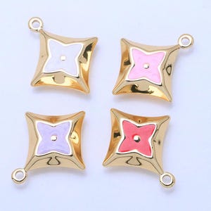 May include: Four gold-colored charms with a star-shaped design. Each charm has a different colored center: white, pink, lavender, and red. The charms have a loop at the top for attaching to jewelry.