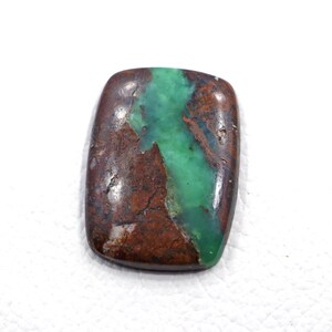 Può includere: Un cabochon di pietra preziosa lucidata di forma rettangolare caratterizzato da una vena centrale verde brillante che attraversa verticalmente una matrice marrone terra profonda con macchie scure e una finitura superficiale liscia e riflettente.