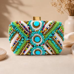 May include: A rectangular clutch bag featuring a vibrant, multi-colored beaded and stone-encrusted exterior. The design includes turquoise-colored stones, bright green, white, and multi-colored seed beads, and a gold-toned metal clasp closure.