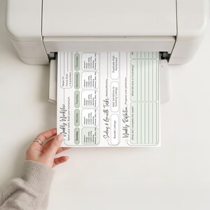 May include: A white printer outputting a paper planner page titled Weekly Workflow. The document features sections for daily tasks, scaling and growth tasks, and a weekly reflection, with light green accents and black text throughout.