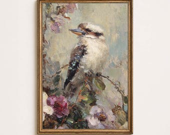 May include: An oil painting in a gold frame depicting a kookaburra perched on a branch. The bird has brown, white, and blue-grey feathers. It is surrounded by textured, painterly flowers in shades of purple, pink, and cream against a soft background.