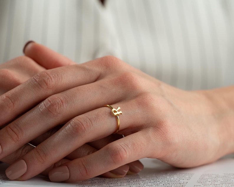 Minimalist ring worn on hand featuring a script initial ring with elegant handwriting lettering