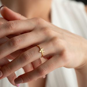 Dainty ring worn on hand featuring a personalized ring with a script initial and everyday jewelry style