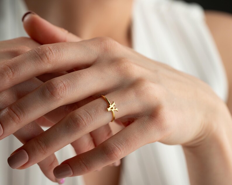 Dainty ring worn on hand featuring a personalized ring with a script initial and everyday jewelry style