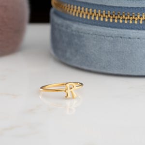 Letter ring displayed on a neutral background showcasing a personalized ring with minimalist handwriting style
