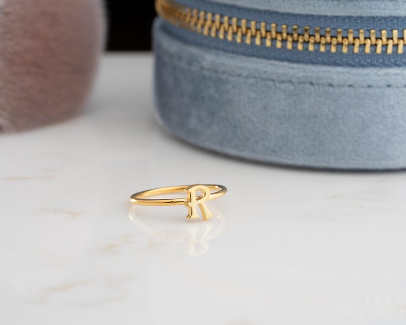 Letter ring displayed on a neutral background showcasing a personalized ring with minimalist handwriting style