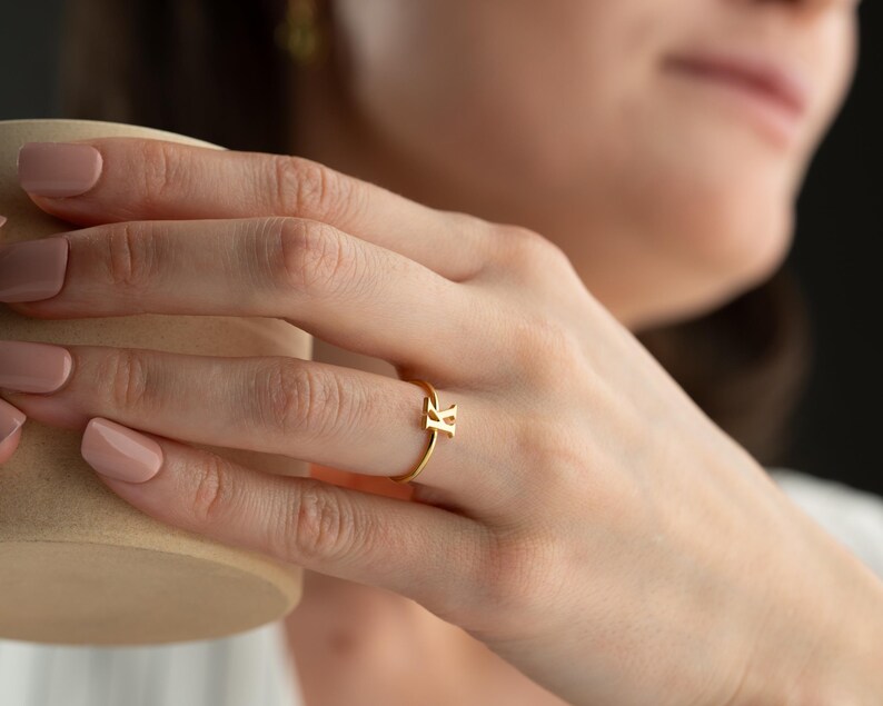 Personalized jewelry worn on model featuring a script initial ring with a custom initial design