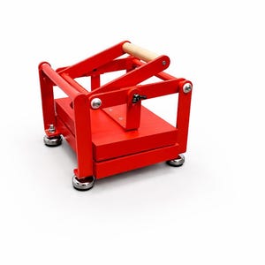 May include: A bright red wooden press with a natural wood handle. The press has a rectangular base and a hinged top, with silver hardware. The press is designed for a specific purpose, likely for crafts or food preparation.