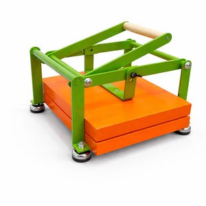 May include: A bright green and orange tortilla press with a wooden handle. The press has a lever design and sits on four small, round feet. The base is a stack of orange wooden boards.