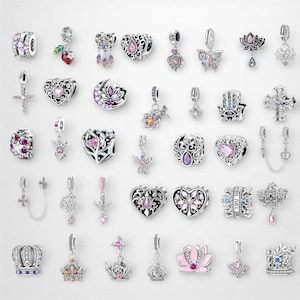 Può includere: Una collezione di charm beads argentati con vari design. Gli charm includono cuori, corone, croci, farfalle e motivi floreali, molti adornati con pietre preziose rosa, viola e blu. Alcuni charm hanno elementi pendenti.