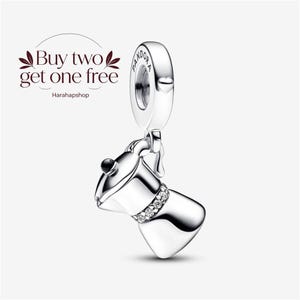 May include: A silver charm shaped like a moka pot coffee maker with a small black knob on the lid and a band of clear stones around the centre. The charm features the word Pandora engraved on the top loop and text reading Buy two get one free.