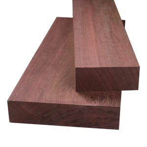 Könnte beinhalten: Drei rechteckige Stücke rotbraunen Hartholzes sind auf weißem Hintergrund gestapelt. Die Holzmaserung ist sichtbar, und die Kanten sind sauber geschnitten. Das Holz scheint frisch geschnitten und für Holzbearbeitungsprojekte geeignet zu sein. Die Dicke beträgt ca. 5 cm.