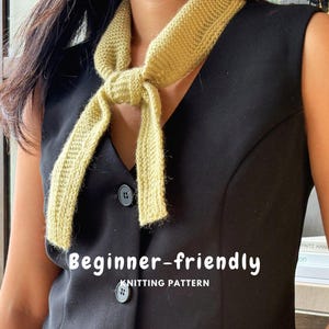 Könnte beinhalten: Ein hellgelber, gestrickter Halsschal mit einfachem Knoten und einer texturierten kraus rechts gestrickten Struktur. Das Bild enthält den weißen Text "Beginner-friendly KNITTING PATTERN" in der Mitte des Kleidungsstücks.