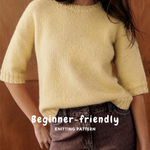 May include: A pale yellow knit sweater with elbow-length sleeves, a round neckline, and ribbed cuffs and hem. The image features the text "Beginner-friendly KNITTING PATTERN" and "ENGLISH PATTERN" in white lettering over the garment.