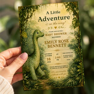 Könnte beinhalten: Eine rechteckige Babyparty-Einladungskarte mit einem grünen Dinosaurier in einer üppigen Dschungellandschaft. Der Text lautet A Little Adventure is on the way, Baby Shower für Emily Rose Bennett, mit Veranstaltungsdetails für den 16. Oktober 2026.