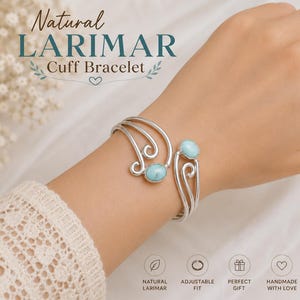 Könnte beinhalten: Ein silbernes Armband mit zwei ovalen, hellblauen Larimar-Steinen, die in geschwungene Metallbänder eingefasst sind. Der Text Natural LARIMAR Cuff Bracelet ist oben zu sehen, zusammen mit Symbolen für natürlichen Larimar, verstellbare Passform, Geschenk und Handarbeit.