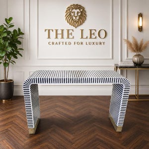 May include: A rectangular console table featuring a continuous waterfall design with a black and white striped pattern. The base of each side is finished with a metallic gold accent. The table has a smooth surface and a curved structure.