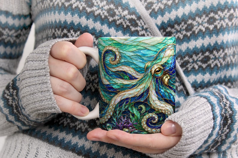 May include: A white ceramic mug featuring a vibrant, stained-glass style illustration of an octopus with swirling tentacles in shades of teal, deep blue, and gold. The design includes intricate patterns and textures, with coral elements at the base.
