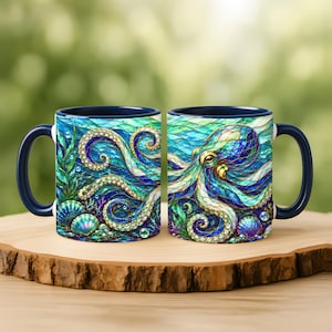 May include: Two ceramic mugs featuring a vibrant, stained-glass style illustration of an octopus surrounded by seaweed, seashells, and bubbles. The design uses shades of blue, teal, and gold, with a solid dark blue handle and interior rim.