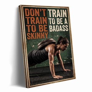 May include: A rectangular wall art print featuring a person performing a weighted push-up with weight plates on their back. The text reads DON'T TRAIN TO BE SKINNY TRAIN TO BE A BADASS in orange and white lettering against a dark green background.