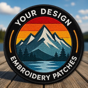 May include: A circular embroidered patch featuring a mountain landscape with a sunset sky in shades of red, orange, and yellow. The design includes blue mountains, dark pine trees, and water. The black border displays the text YOUR DESIGN EMBROIDERY PATCHES.