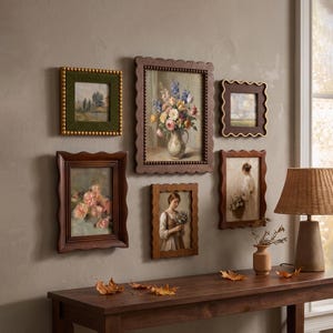 Könnte beinhalten: Eine Galerie-Wand mit sechs gerahmten Kunstwerken in verschiedenen Holz- und Texturrahmen. Die Sammlung umfasst Gemälde von Blumensträußen, Landschaften und einer Person mit Blumen, angeordnet über einem hölzernen Konsolentisch.