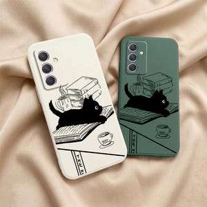 以下が含まれることがあります： クリーム色とダークグリーンの長方形のスマホケース2つ。どちらも開いた本の上に寝そべる猫、本の山、コーヒーカップの黒い線画が描かれており、下部にはTHE Nという部分的なテキストが含まれています。