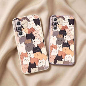 May include: Two rectangular smartphone cases featuring a dense, repeating pattern of cartoon cats in various shades of white, cream, brown, grey, and black. The cases have cutouts for camera lenses and are displayed side by side on a soft fabric.