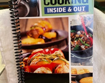 May include: A spiral-bound cookbook titled "Cast Iron Cooking Inside & Out." The cover features images of cast iron cookware and prepared dishes. The book includes directions for indoor and outdoor cooking for each recipe.