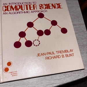 May include: A white textbook titled An Introduction to Computer Science: An Algorithmic Approach by Jean-Paul Tremblay and Richard B. Bunt. The cover features a dark red tree diagram with nodes and lines, and a small orange logo in the corner.