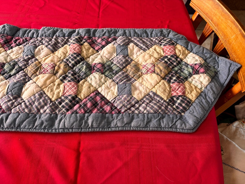K&ouml;nnte beinhalten: Gesteppter Tischl&auml;ufer mit Rautenmuster. Der L&auml;ufer hat ein Patchwork-Design mit Quadraten aus karierten und unifarbenen Stoffen in Beige-, Rosa-, Gr&uuml;n- und Graut&ouml;nen. Die Kanten sind mit einem grauen Rand versehen.