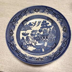 以下が含まれることがあります： 柳の伝統的な模様が施された青と白のセラミックボウル。ボウルには、橋、木々、パゴダの細かなデザインが施されています。