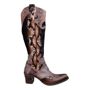 May include: A high-heeled cowboy boot in brown and tan with a snakeskin design. The boot has a pointed toe, a stacked heel, and decorative stitching. The boot's shaft is decorated with a snakeskin print in shades of brown, tan, and black.