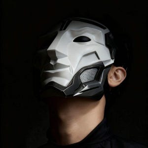 May include: A futuristic full-face mask featuring a white, angular, geometric upper section and a contrasting black lower jaw piece. The design includes metallic silver accents, a mesh-covered cheek vent, and sharp, defined facial contours.