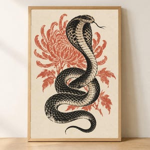 Pode incluir: Uma impressão de arte emoldurada apresentando uma ilustração a preto e branco de uma cobra com o capuz aberto e a língua de fora, posicionada à frente de um grande crisântemo laranja-avermelhado detalhado num fundo creme claro.