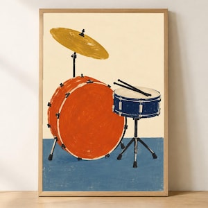 May include: A framed wall art print featuring a stylized illustration of a drum kit. The kit includes a large orange bass drum, a smaller blue snare drum with two black drumsticks resting on top, and a single yellow cymbal on a black stand.
