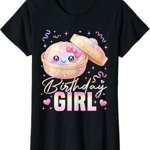 Può includere: Una t-shirt nera a maniche corte con la grafica di un grazioso gnocco iridescente in un cestello per la cottura a vapore in bambù con un fiocco rosa. Il testo Birthday GIRL è in un font sfumato, circondato da coriandoli, stelle e cuori rosa.