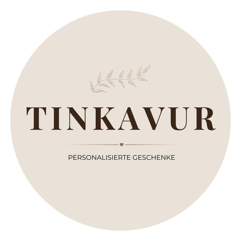 May include: A circular logo with the word "TINKAVUR" in dark brown, centered on a light beige background. Below the text is "PERSONALISIERTE GESCHENKE" in a smaller font. A small leaf design is at the top.