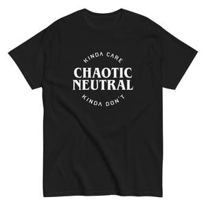 May include: A black short-sleeve t-shirt featuring a white circular graphic on the chest. The text reads KINDA CARE in an arc at the top, CHAOTIC NEUTRAL in large bold letters in the center, and KINDA DON'T in an arc at the bottom of the circle.
