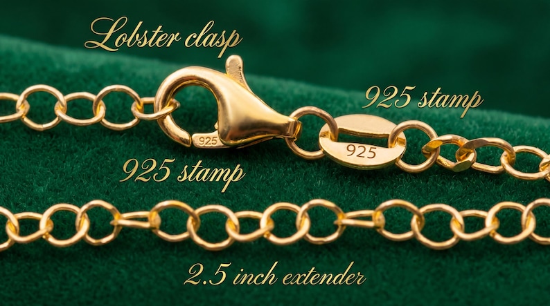 Puede incluir: Primer plano de una cadena de collar dorada con un cierre de mosquet&oacute;n y una extensi&oacute;n de 6,35 cm. La cadena tiene un sello 925. El fondo es de tela verde oscuro.
